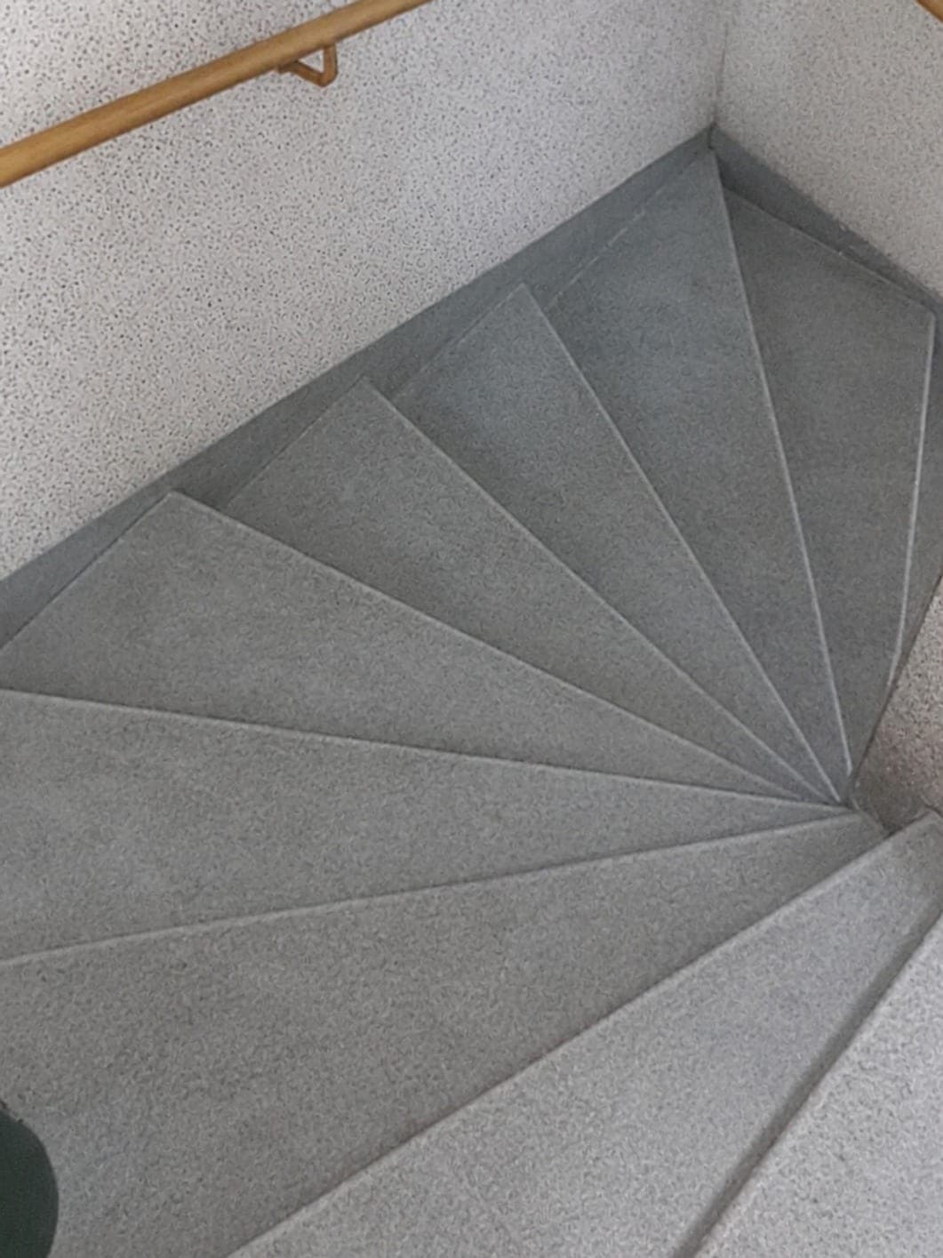 Marches grises propres d'un escalier en colimaçon, main courante en bois