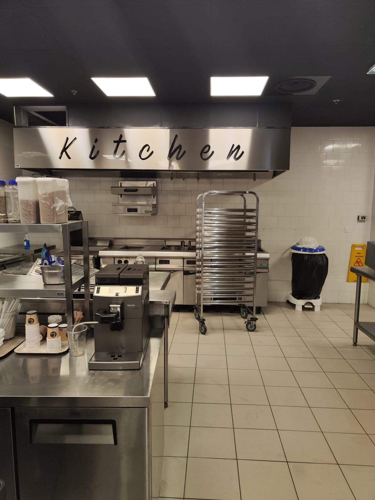 Cuisine de restaurant propre, chariot inox devant les friteuses, sous la hotte
