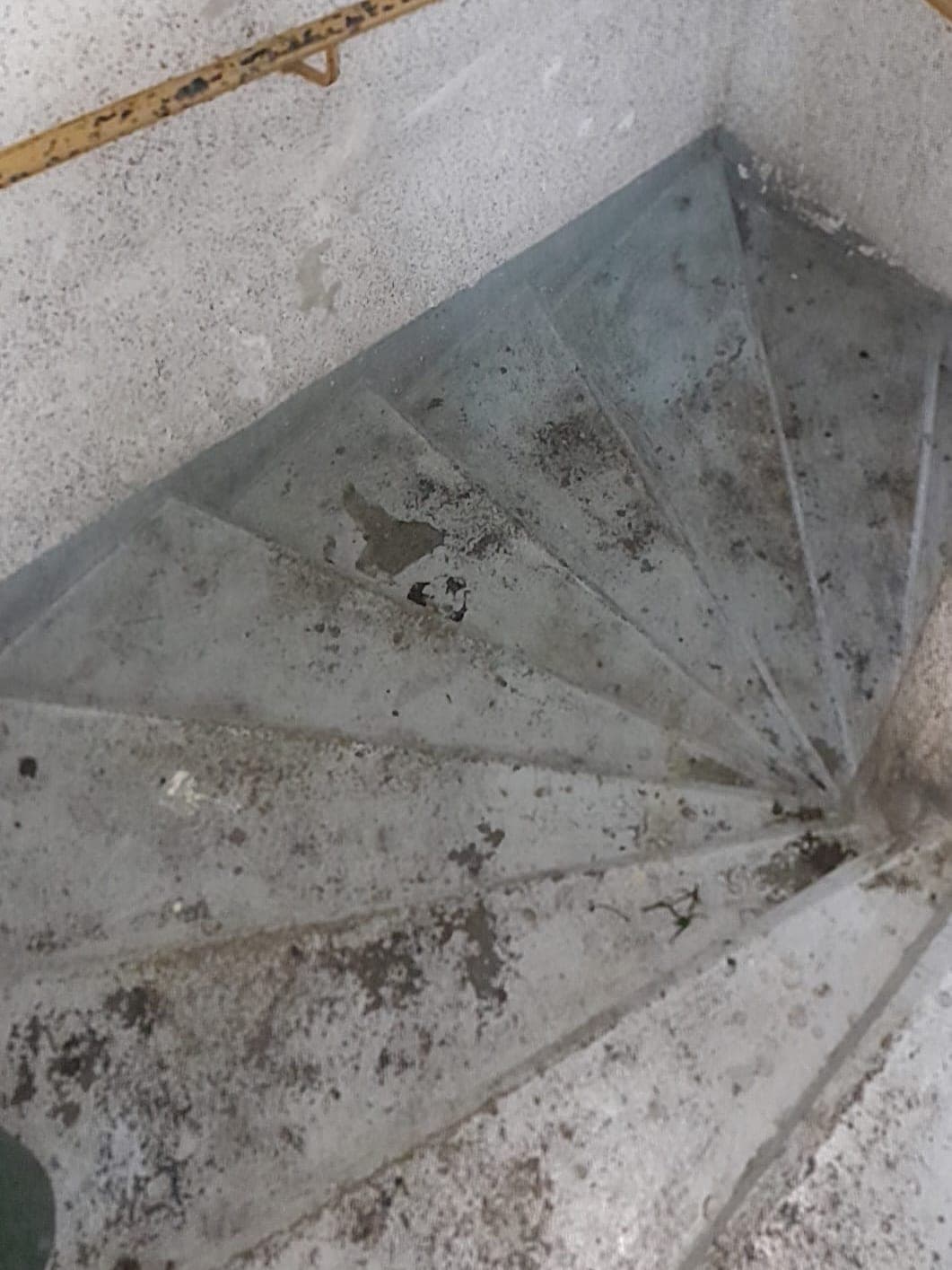 Escalier en colimaçon et sa main courante, marches tachées de terre